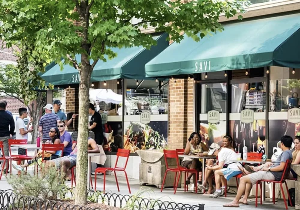 A small-format Savi with sidewalk seating under green awnings